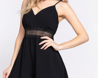 A woman wearing a black lace-trim cami romper