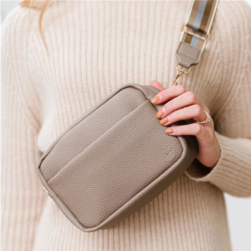 Black leather wide strap crossbody bag worn across the body